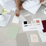 Designer sits on carpet with color palettes and samples, planning creative project.