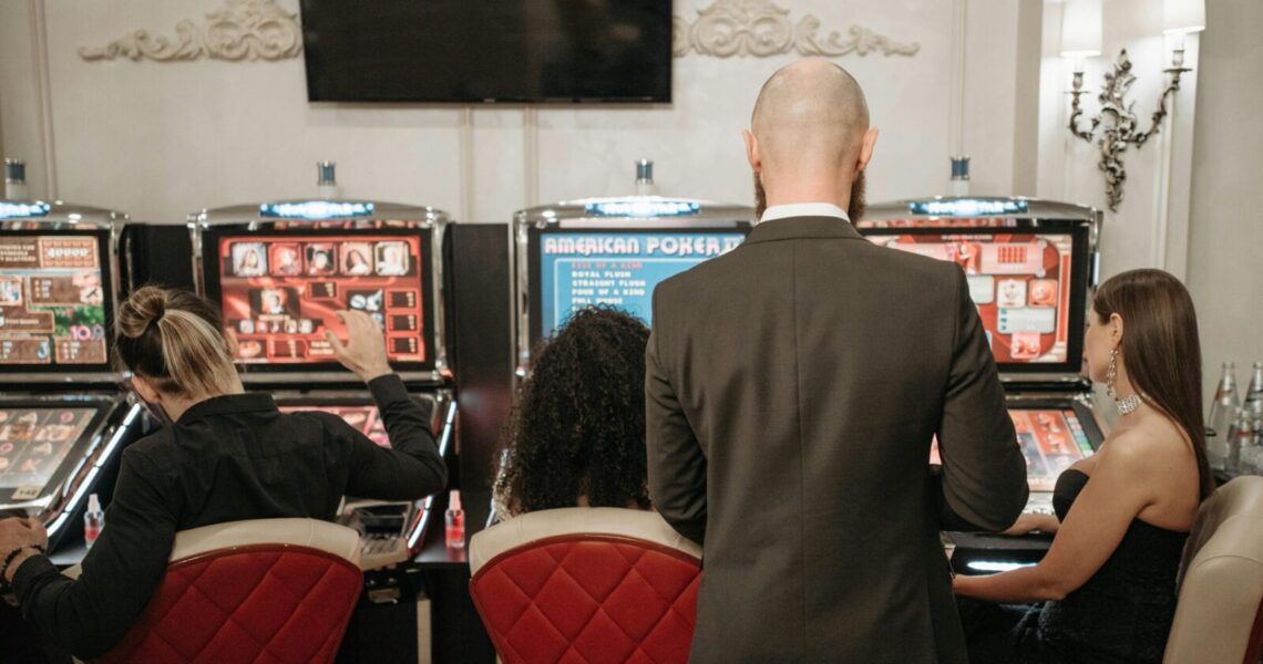 A group of adults engaged in playing slot machines inside a stylish casino setting.