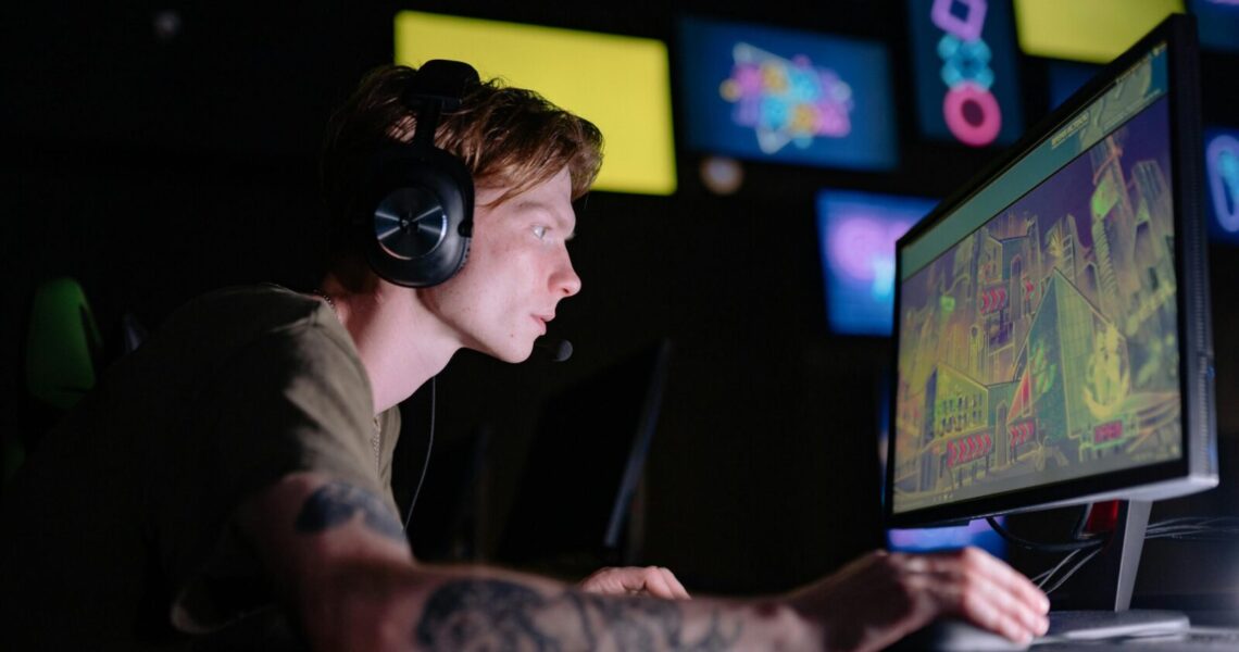 Engaged gamer wearing headphones intensely playing on a computer monitor indoors.